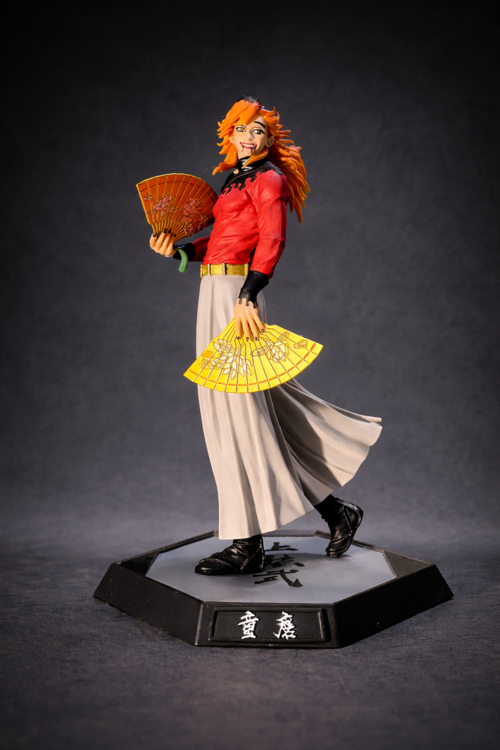 Statue of a character with orangish hair and traditional outfit holding fans on a dark background