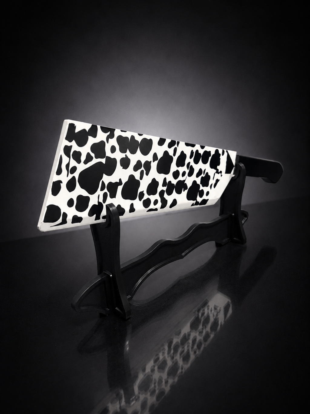 Angled view of cow pattern anime butcher blade replica with black handle on premium display stand for cosplay and collectors