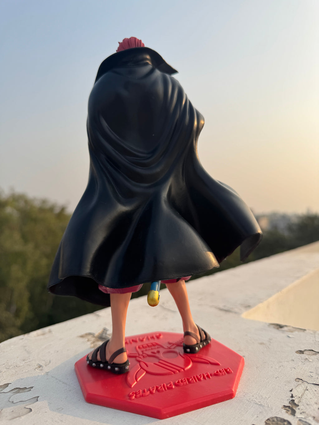 Person wearing a black coat and sandals stepping onto a red platform.