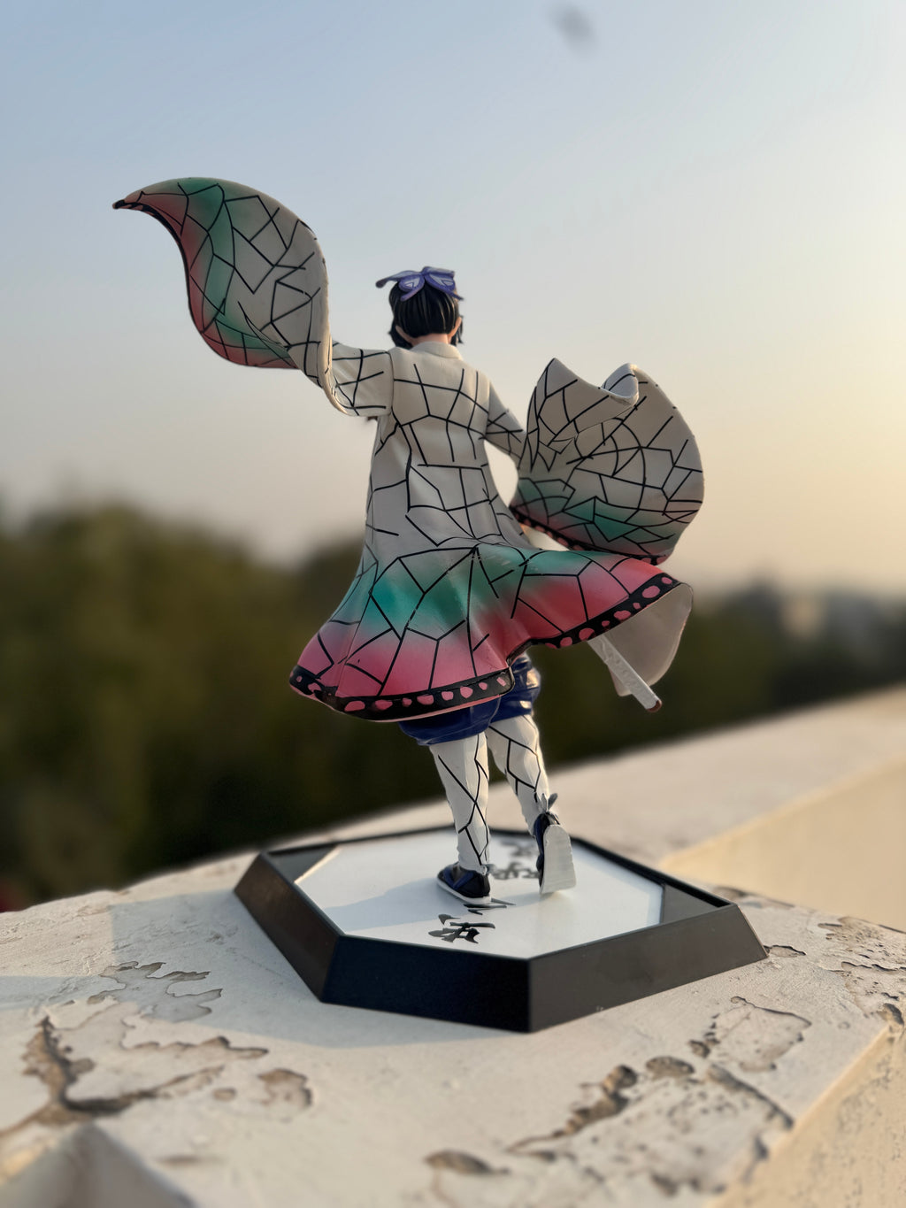 Colorful figurine with geometric design on a stand against a blurred natural background