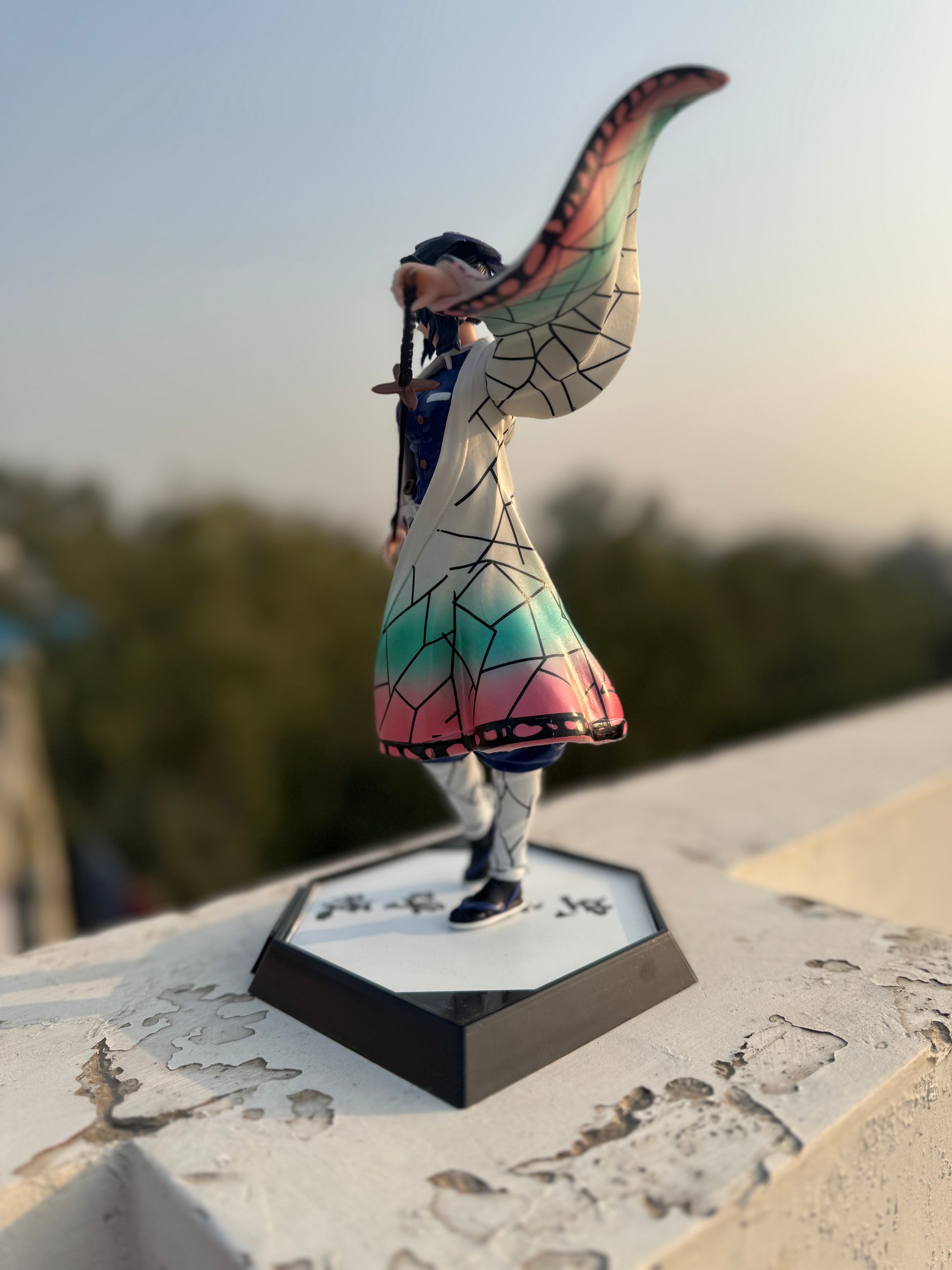 Colorful fairy figurine on a hexagonal base with a blurred natural background
