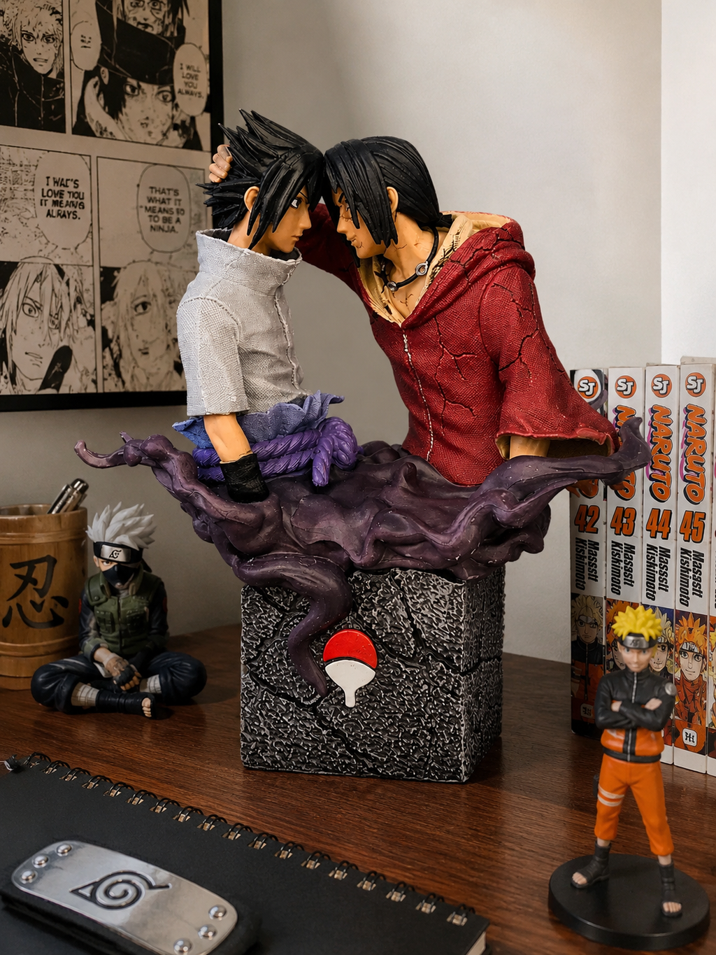 A Naruto anime collectible figurine set on a wooden desk, featuring the Sharingan lovers sculpture with a purple chakra swirl base, surrounded by Naruto manga books and other character figures.